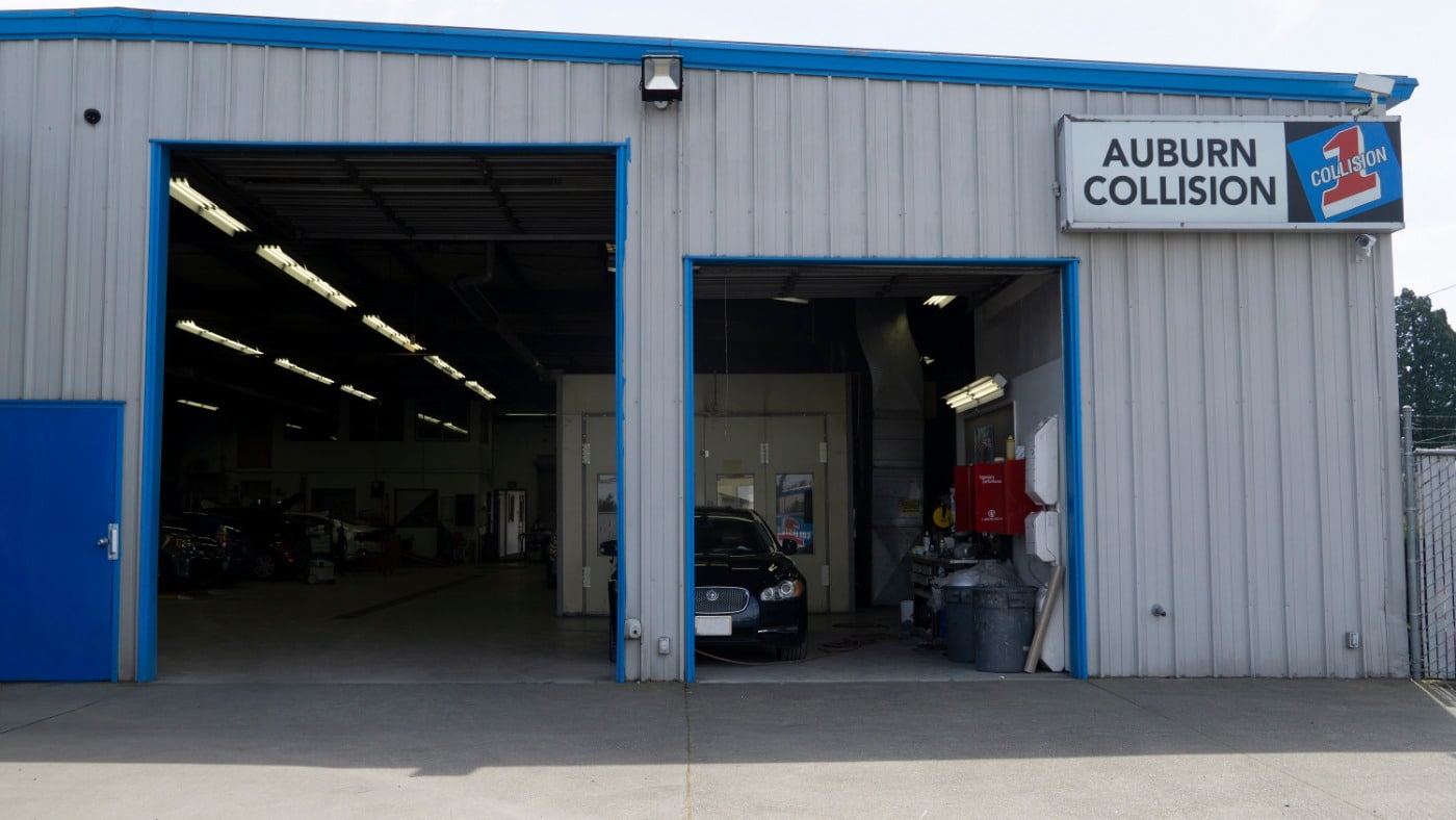 Frontal exterior view of an auto body repair shop with a sign displaying text that reads, Auburn Collision
